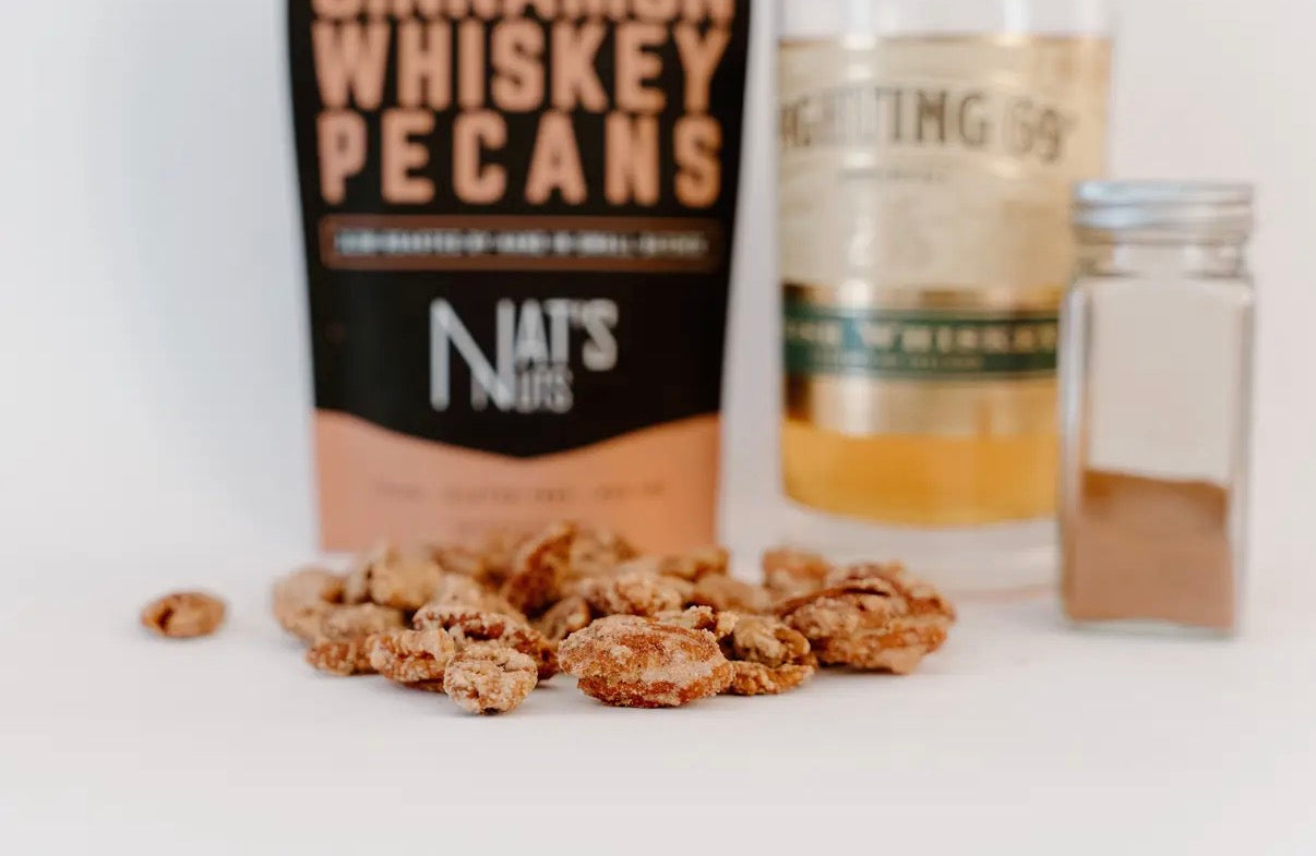 Dinah's Whiskey Pecans with a bottle of whiskey on a white surface