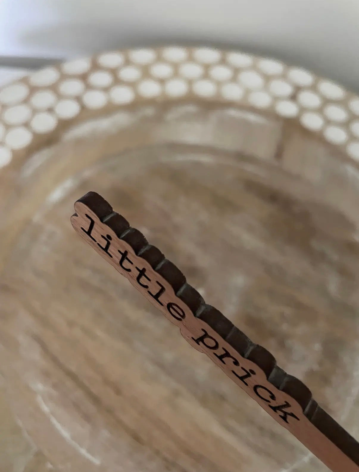 wooden stake with 'little prick' text on a textured background