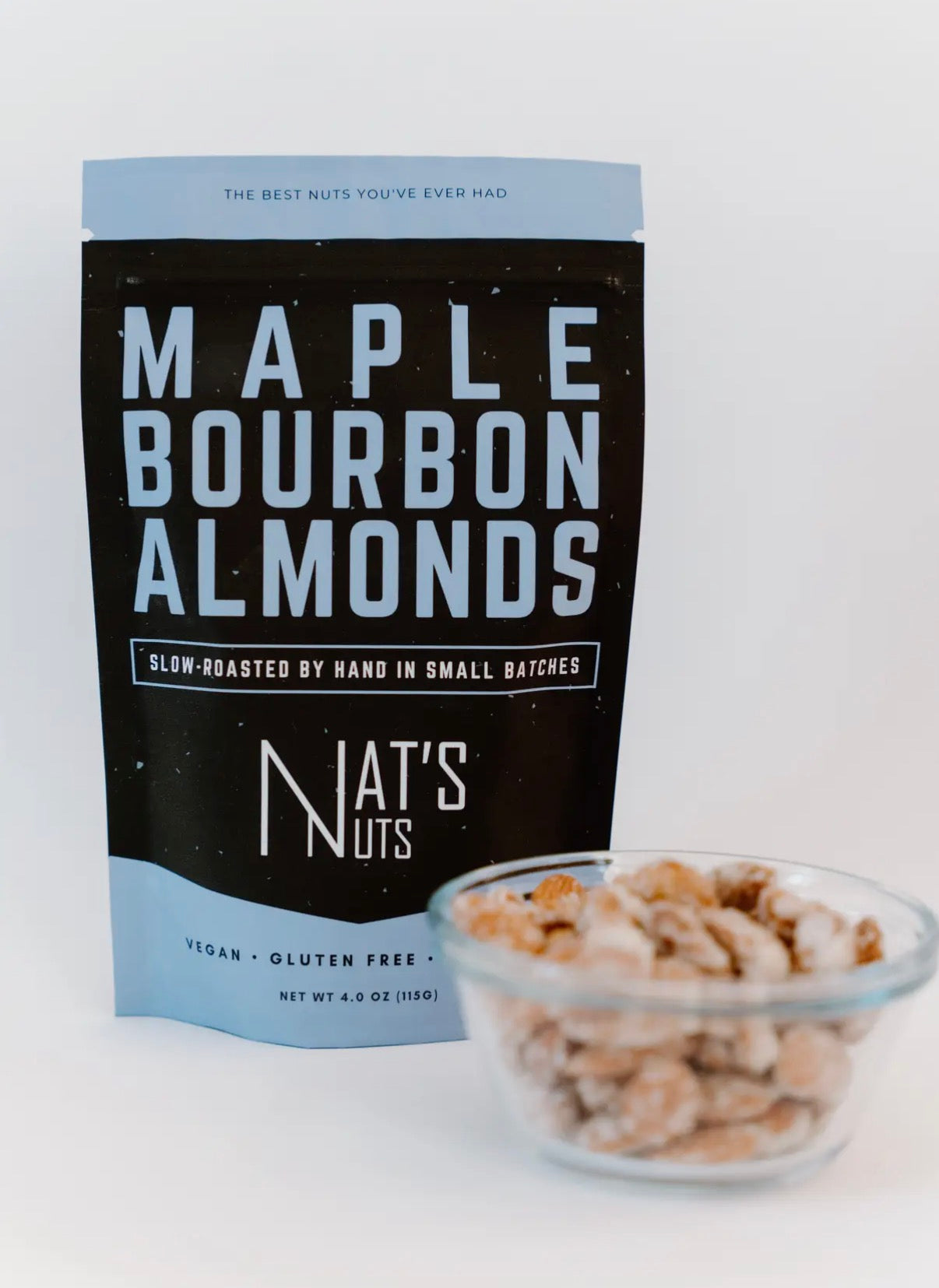 Bag of Maple Bourbon Almonds from Nat's Nuts with a bowl of almonds on a white background